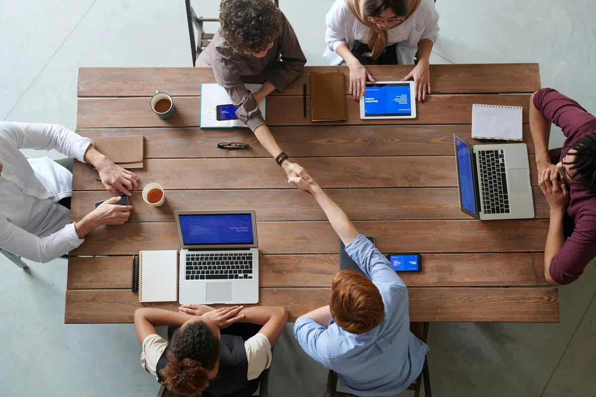 Une équipe réunie autour d’une table de travail, ordinateurs et tablettes ouverts