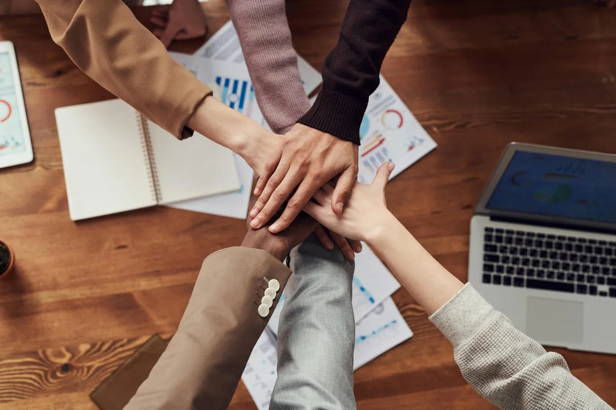 Mains d’une équipe réunies au-dessus d’une table de travail